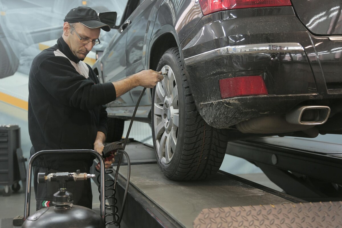 Mobile tire air inflation service Waikiki Oahu — uniformed technician filling tire pressure with portable air compressor in Honolulu