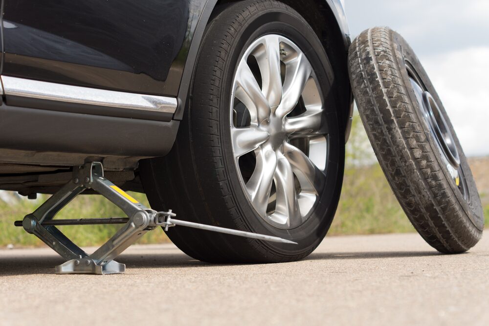 Flat tire being changed roadside Honolulu Hawaii — jack and lug wrench mobile tire replacement Waikiki